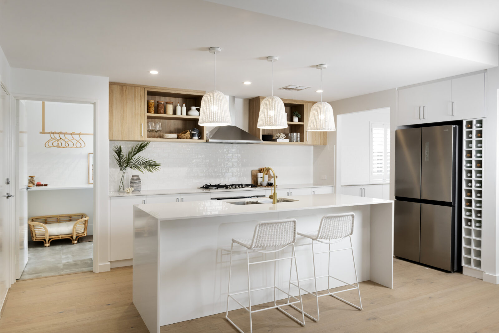 Contemporary white Australian kitchen with island featuring soft overhead lighting constructed by home builders in WA